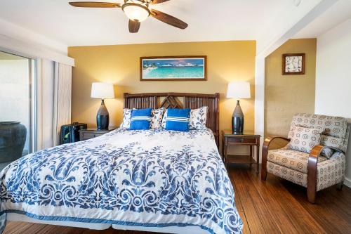 a bedroom with a blue and white bed and a chair at Keauhou Resort 113 in Kailua-Kona