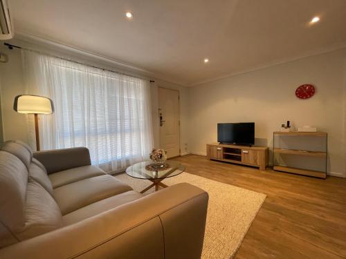 a living room with a couch and a television at Vestey Apartments in Wagga Wagga
