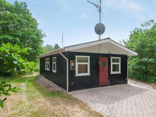 een zwart-wit tiny house met een rode deur bij Holiday Home Hilde - 1-7km from the sea in NE Jutland by Interhome in Sæby