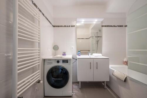 une salle de bain blanche avec une machine à laver et un lavabo dans l'établissement *Disneyland-Paris* 7pers, Wifi, Netflix, parking, à Montévrain