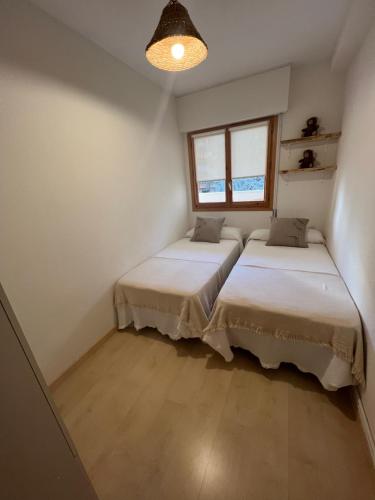 2 Betten in einem kleinen Zimmer mit Fenster in der Unterkunft Apartamento Muga in Jaca