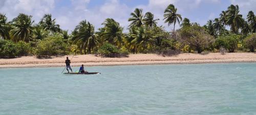 two people are standing on a paddle board in the water at Vila Sol Chalés in Pôrto de Pedras