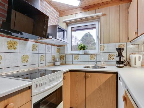 uma cozinha com um fogão, um lavatório e uma janela em Holiday Home Anemarie - 450m from the sea in NE Jutland by Interhome em Sæby