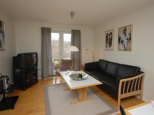 - un salon avec un canapé noir et une table dans l'établissement Apartment Runhild - 100m from the sea in NE Jutland by Interhome, à Hals