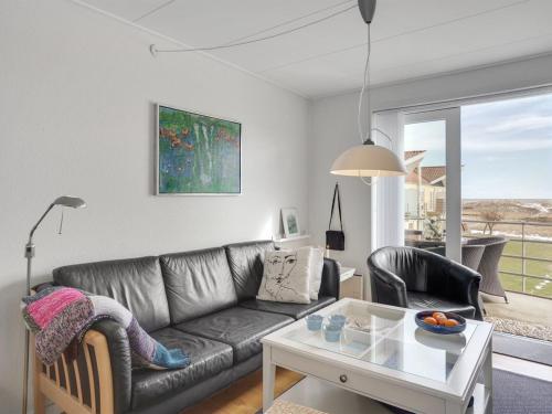 a living room with a leather couch and a table at Apartment Dafna - 100m from the sea in NE Jutland by Interhome in Hals