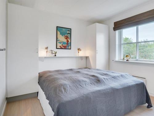 een witte slaapkamer met een groot bed en een raam bij Apartment Sipi - 100m from the sea in NE Jutland by Interhome in Hals