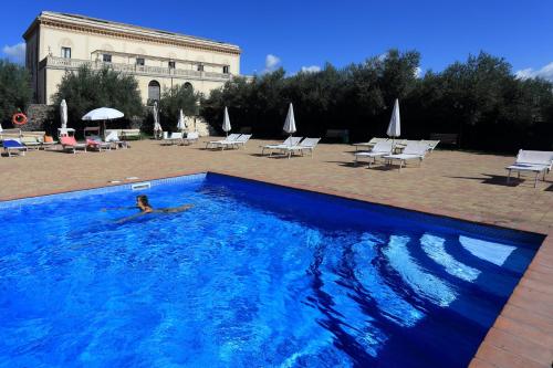 a person swimming in a large blue swimming pool at Feudo Vagliasindi -Wine Experience- in Randazzo