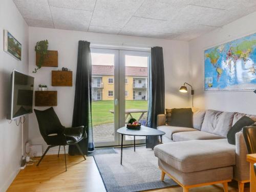 uma sala de estar com um sofá, uma mesa e uma janela em Apartment Amaryllis - 100m from the sea in NE Jutland by Interhome em Hals