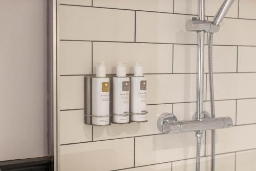 łazienka z 3 butelkami szamponu na ścianie w obiekcie Royal Oak w mieście Cartmel