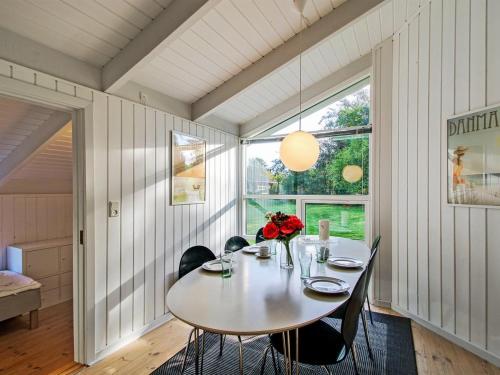 een eetkamer met een tafel en stoelen en een raam bij Holiday Home Clari - 500m from the sea in NE Jutland by Interhome in Hals