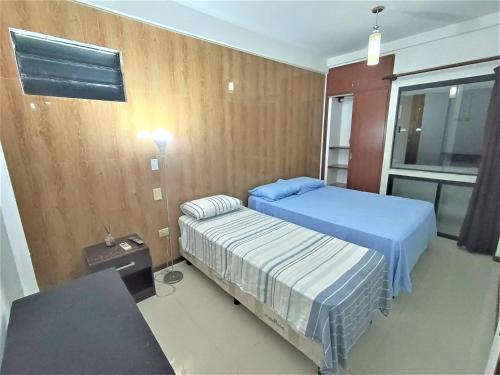 a bedroom with two beds and a table and a window at Departamentos en Edificio Acrebol Santa Cruz in Santa Cruz de la Sierra