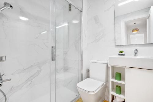 een witte badkamer met douche en toilet bij Paloma's Cozy Beach Flat in Torremolinos