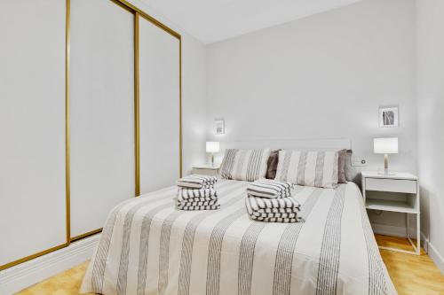 een witte slaapkamer met een bed met 2 kussens erop bij Paloma's Cozy Beach Flat in Torremolinos