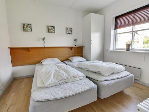 Ce lit se trouve dans un dortoir doté de murs blancs et d'une fenêtre. dans l'établissement Apartment Osfrid - 100m from the sea in NE Jutland by Interhome, à Hals