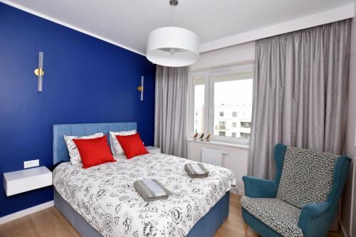 a blue bedroom with a bed and a chair at Apartament Nr 50, 2 sypialnie, wygodny parking podziemny in Toruń