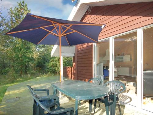 a table and chairs with an umbrella on a patio at Holiday Home Jussi - 3-5km from the sea in NW Jutland by Interhome in Brovst