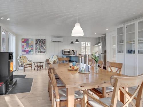 Il comprend une cuisine et une salle à manger avec une table et des chaises en bois. dans l'établissement Holiday Home Marise - from the sea in NE Jutland by Interhome, à Hals