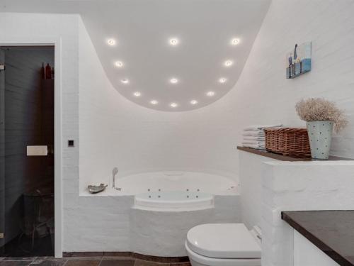 La salle de bains blanche est pourvue d'une baignoire et de toilettes. dans l'établissement Holiday Home Angelarij - all inclusive - from the sea by Interhome, à Hadsund