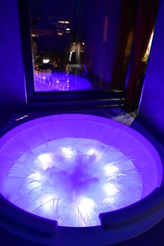 eine große lila Badewanne mit Beleuchtung in einem Zimmer in der Unterkunft Smart Luxury Penthouse Suites - Private Sauna, Hot-Tub, Home Cinema at the best Location in Skopje in Skopje