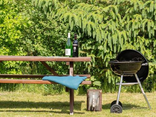a picnic table with a grill and a bottle of wine at Holiday Home Soraya - 700m to the inlet by Interhome in Løgsted
