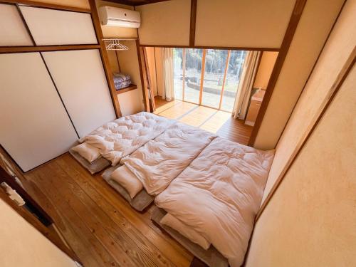 a large bed in a room with a large window at 一軒家貸切 ARUYOguesthouse BBQと焚き火ができる宿 