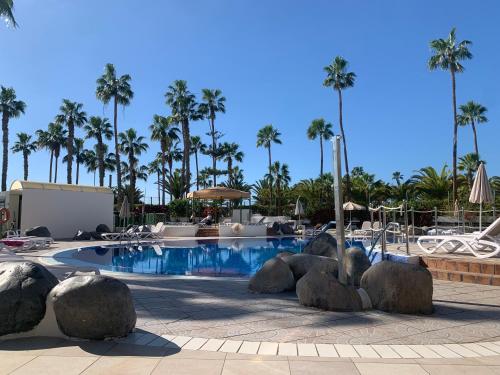 a pool at a resort with rocks and palm trees at ALTAMIRA FAMILY APARTMENT El Duque in Adeje