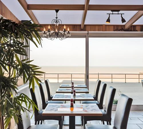 une longue table dans un restaurant avec des chaises et un lustre dans l'établissement Hotel De Zeebries, à Middelkerke