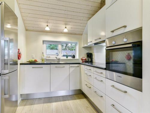 een keuken met witte kasten en een wastafel bij Holiday Home Anethe - 100m to the inlet in The Liim Fiord by Interhome in Løgstør