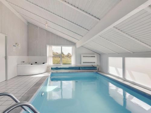 a bathroom with a large swimming pool with a tub and a sink at Holiday Home Serine - 800m from the sea in NW Jutland by Interhome in Hjørring
