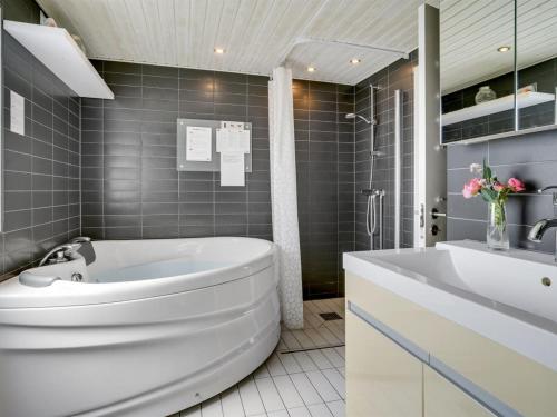 ein Badezimmer mit einer weißen Badewanne und einem Waschbecken in der Unterkunft Holiday Home Edel - 650m from the sea in NE Jutland by Interhome in Hadsund