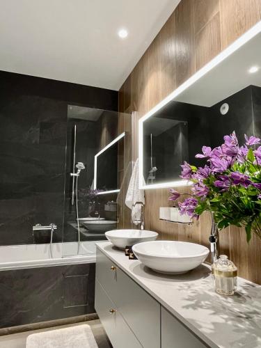 a bathroom with two white sinks and a bath tub at Apartament Hawkinsa in Jelenia Góra