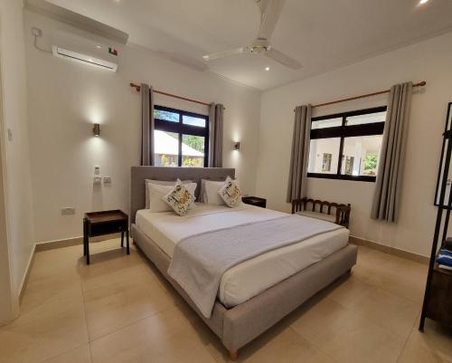 ein Schlafzimmer mit einem großen Bett und zwei Fenstern in der Unterkunft Villa Laure in Grand'Anse Praslin