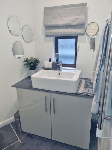 a bathroom with a white sink and a window at The Den - A modern, quirky room, new for 2023. in Braunton