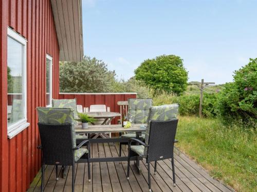 drewniany taras ze stołem i krzesłami na czerwonym domu w obiekcie Holiday Home Stella - 700m from the sea in NW Jutland by Interhome w mieście Hjørring