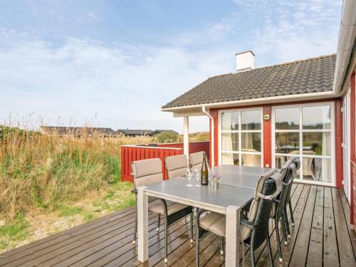 een houten terras met een tafel en stoelen erop bij Holiday Home Iacobus - 400m from the sea in NW Jutland by Interhome in Hjørring