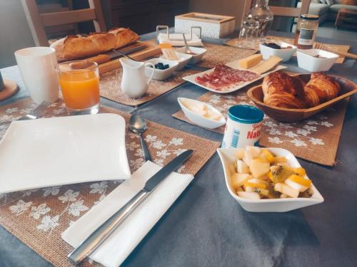 a table with a breakfast of croissants and a plate of food at L'Ansolanette - Chambre d'hôtes in Fuveau
