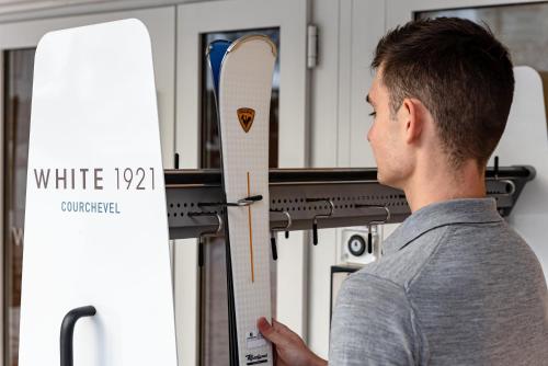 a man standing in front of a stove holding a snowboard at White 1921 Courchevel in Courchevel