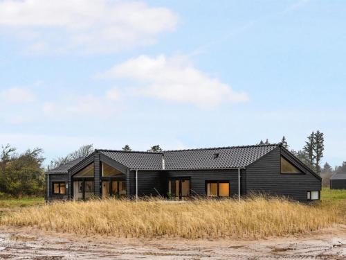 een zwart huis aan de zijkant van een veld bij Holiday Home Sasja - 1-5km from the sea in NW Jutland by Interhome in Hjørring