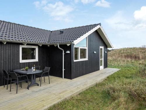 czarny dom ze stołem na drewnianym tarasie w obiekcie Holiday Home Frejdis - 1-1km from the sea in NW Jutland by Interhome w mieście Hirtshals