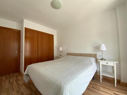 1 dormitorio con cama blanca y puerta de madera en LETS HOLIDAYS Quiet apartment with pool in tossa en Tossa de Mar