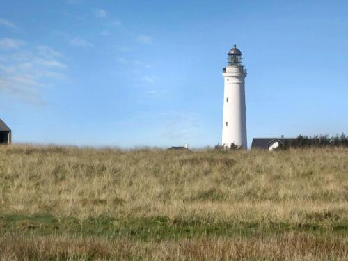 a lighthouse sitting on top of a grassy field at Holiday Home Simona - 300m from the sea by Interhome in Hirtshals