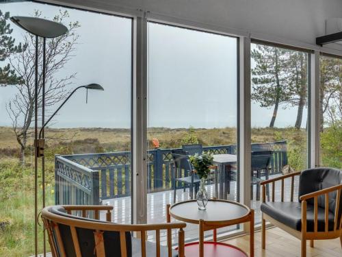 Cette chambre dispose de grandes fenêtres, de tables et de chaises. dans l'établissement Holiday Home Djuna - 200m from the sea in NE Jutland by Interhome, à Læsø