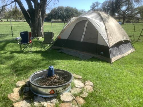 una tienda y una parrilla en la hierba junto a una hoguera en Constantino Farms Campsites Tent Camping, en Wilson