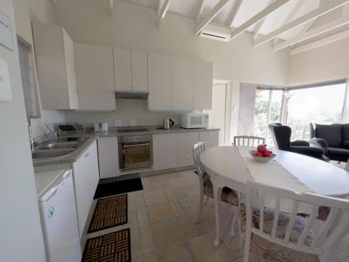 a kitchen with white cabinets and a table and chairs at Orangerie Guest House in Johannesburg