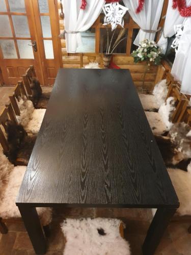a dark wooden table in a room with sheep at Rooms Poienita in Slănic-Moldova