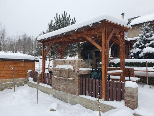 a wooden gazebo with snow on top of it at Rooms Poienita in Slănic-Moldova