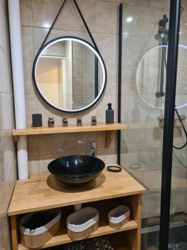 une salle de bain avec un lavabo noir et un miroir dans l'établissement Appartement Type 3 face mer, à Saint-Hilaire-de-Riez
