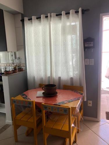 a dining room table and chairs with a white curtain at Apartamento Elizabetta 3, pé na areia in Arraial do Cabo