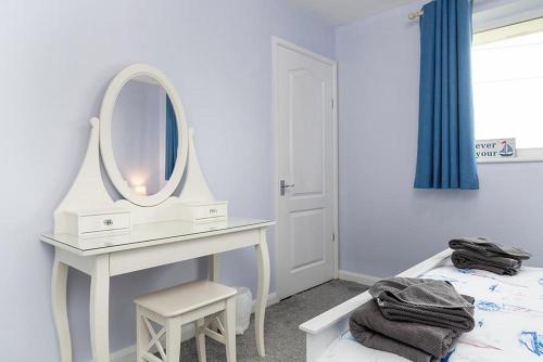 a bedroom with a dressing table and a mirror at Pebbles Reach in Llanddulas