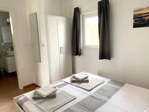 een witte kamer met een bed en een raam bij Apartments Cvijet Mora Sreser in Sreser